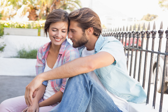 Happy couple sitting and cuddling on a sunny day in the city - How To Keep A Scorpio Man Once You Get Him